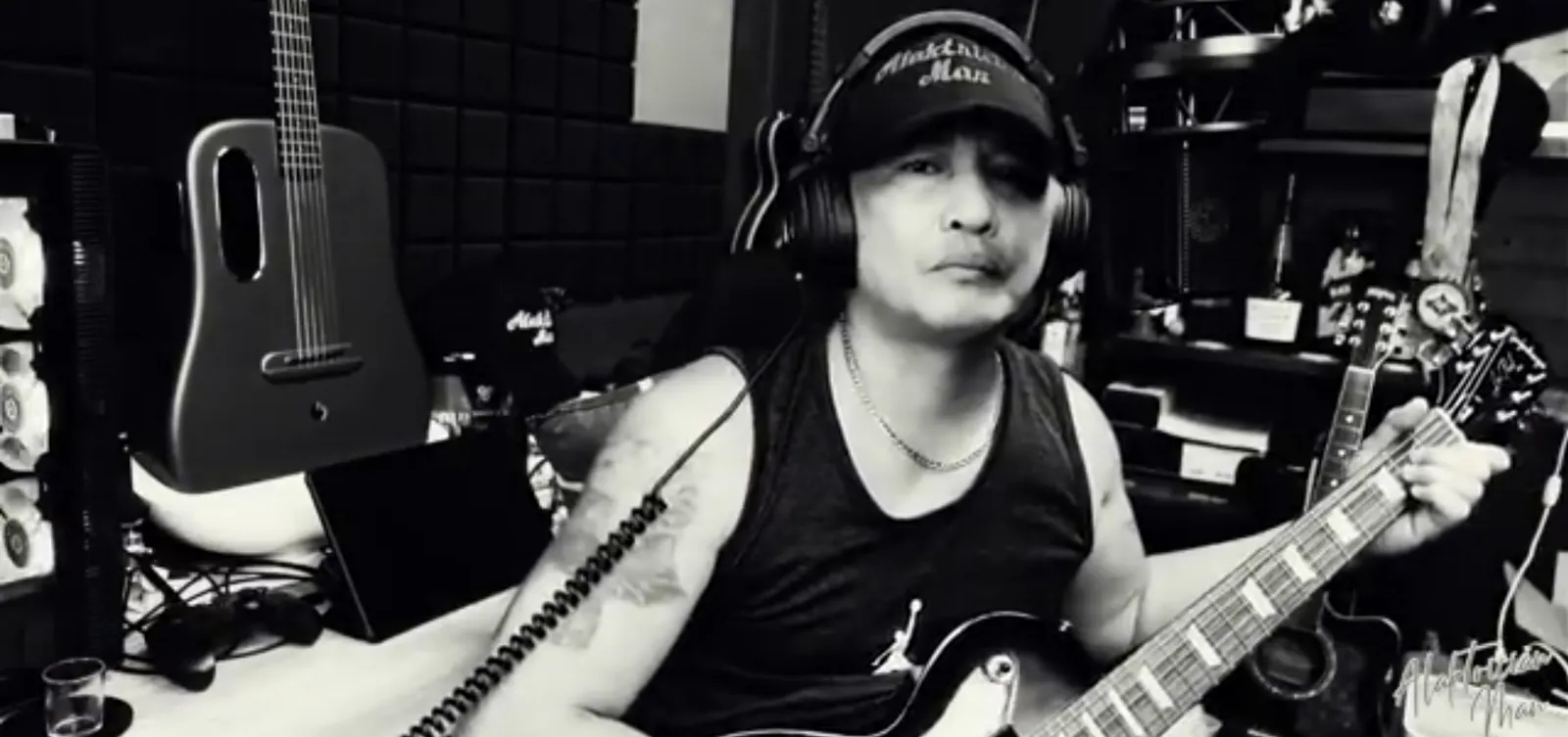 Performer holding a guitar in a recording studio.